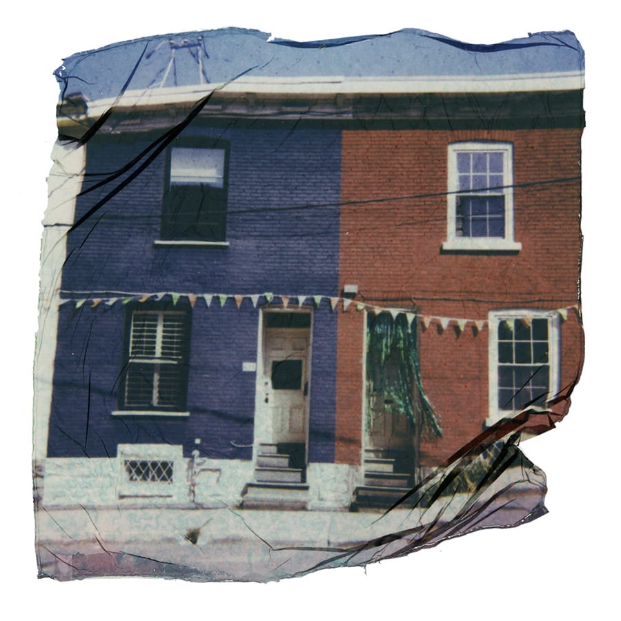 Front of a duplex, left  side painted blue, red on the right, with streamers made white triangles hanging in front. 