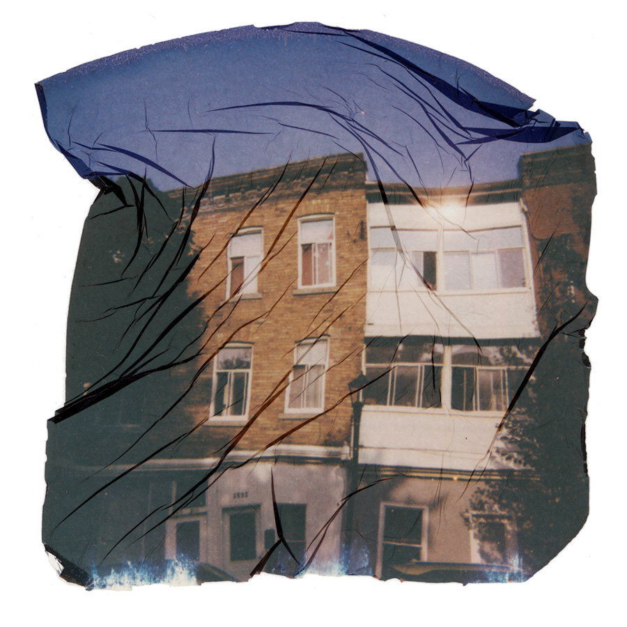 Three story apartment blocks, one brown brick and one white. The white building has the sun shining on its windows creating a sun burst.