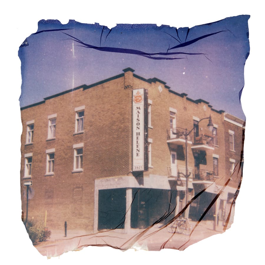Corner of a large brick building on a sunny day with blue sky. On the corner of the building a large sign reads Maison Helene.