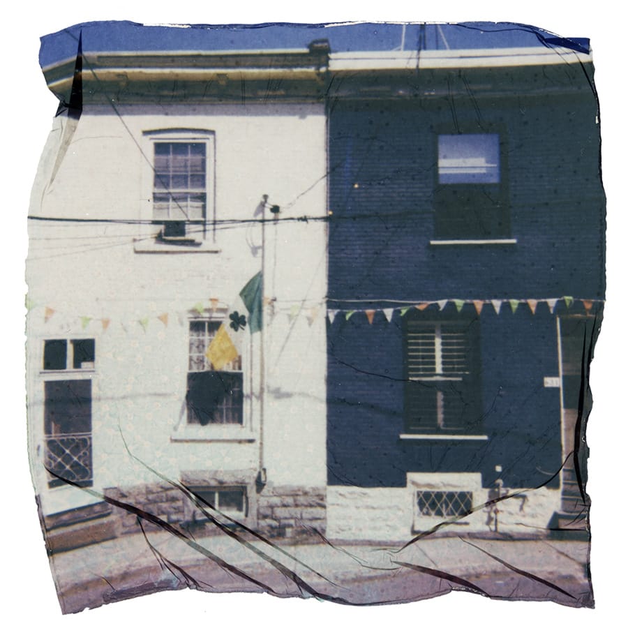 A two story duplex, painted white on the left and blue on the right. An Irish flag with a shamrock in the middle is hung on the left and streamers of small triangles are hung across the entire building.